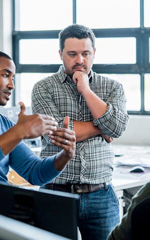 A photo of businessman sharing ideas with colleagues at workplace. Confident male professional is discussing with coworkers. They are wearing smart casuals in creative office.